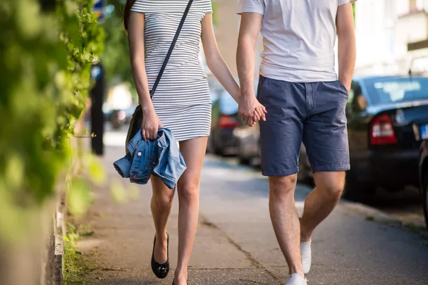 A couple holding hands while walking down a path