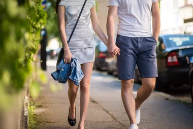 A couple holding hands while walking down a path