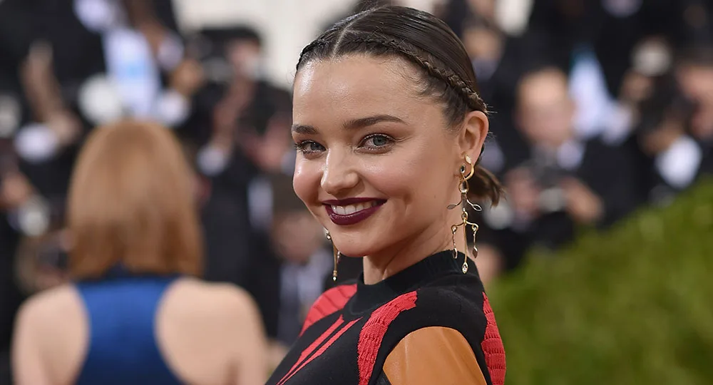 "Person smiling at a formal event, wearing a stylish dress with braided hair and drop earrings."