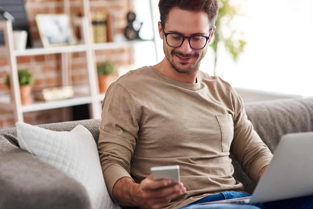 Guy sitting on couch while sending a text on his phone