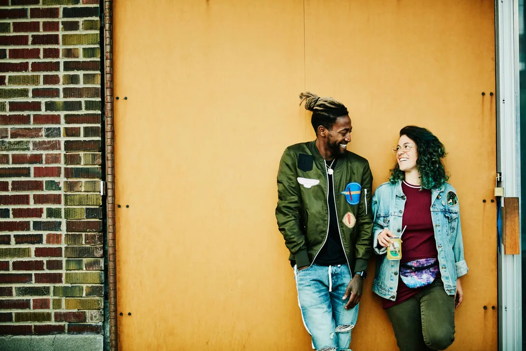 Two people standing against yellow wall