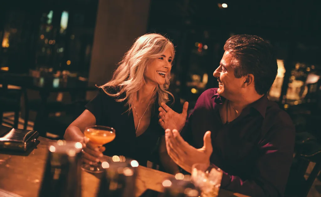 Two people laughing while having drinks on a date