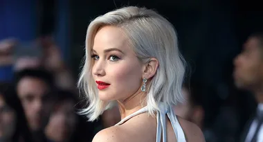 ```html
<img src="image.jpg" alt="Person with blonde hair and red lips, wearing a halter dress and earrings at an event." />
```