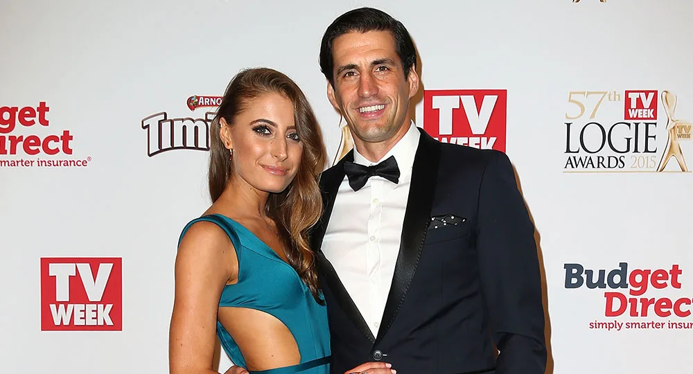 Couple posing on the red carpet at the TV Week Logie Awards, man in a tuxedo and woman in a teal dress.