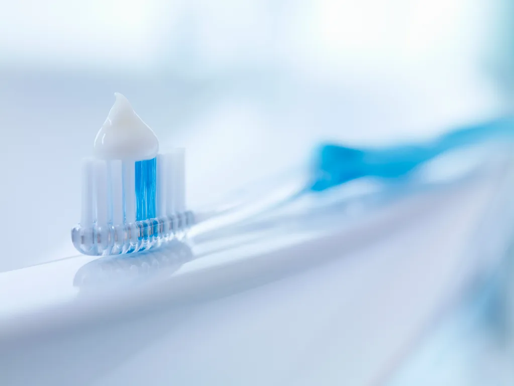 A blue and clear toothbrush with toothpaste on it