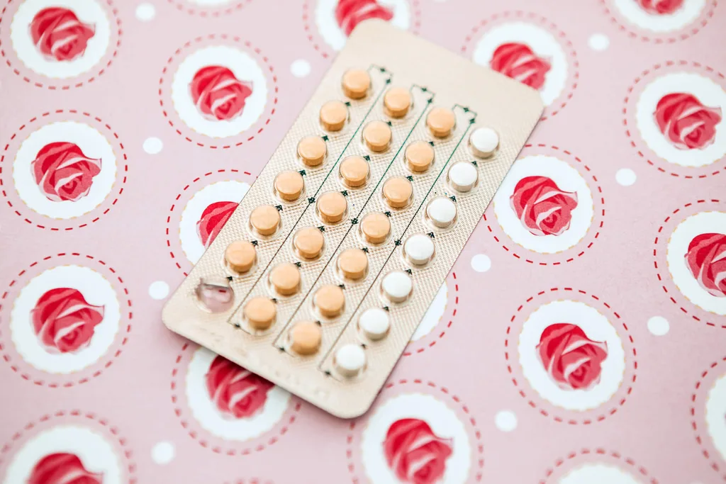A packet of birth control pills lying on a rose pattern sheet