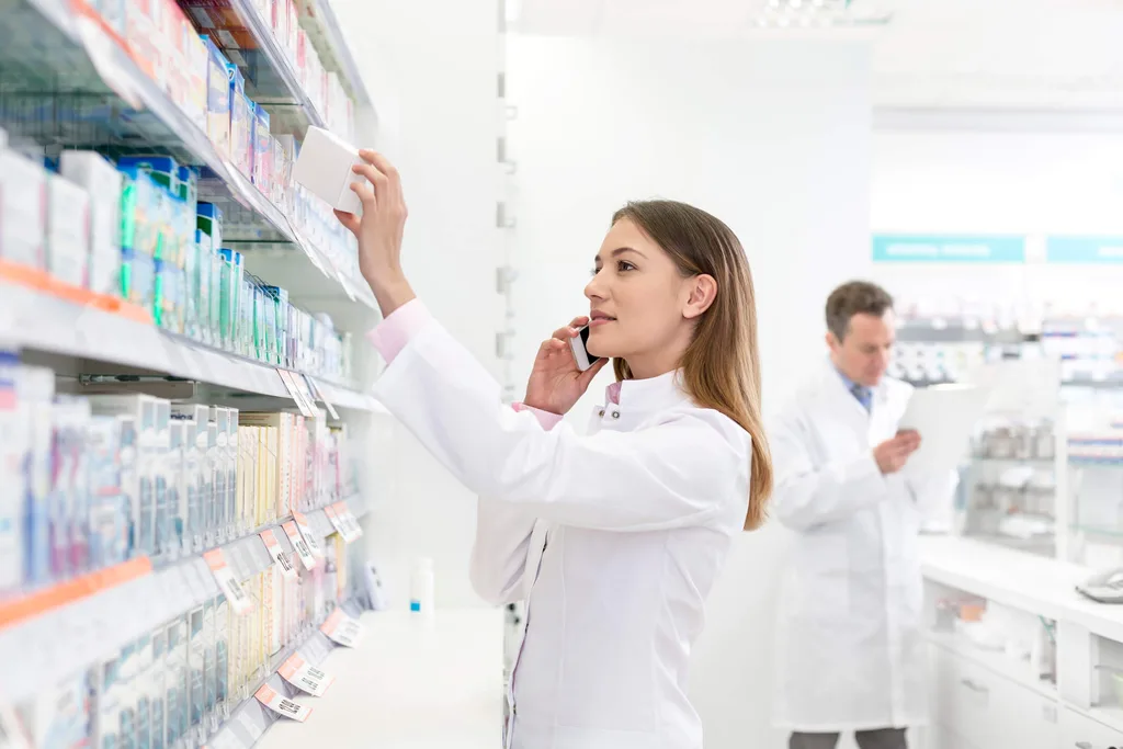 A pharmacist in a white lab coat reaching to get medication off the shelf