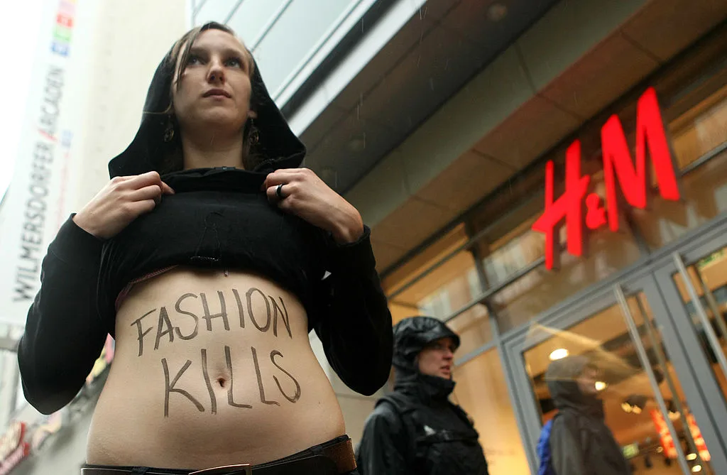 A protester with the text 'FASHION KILLS' written on her stomach,outside a H&M protesting sweatshops