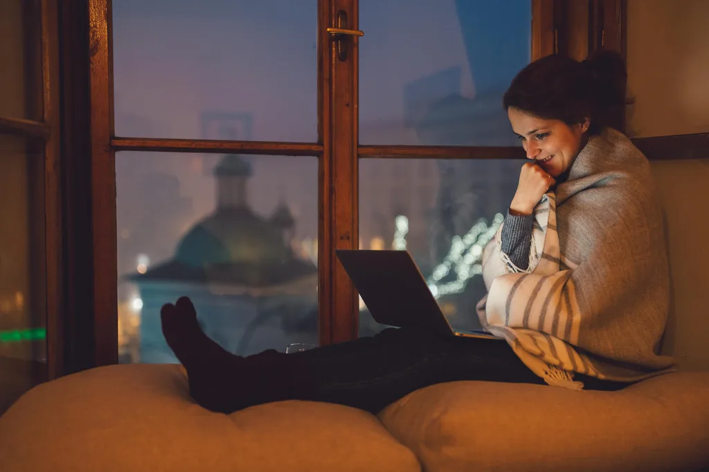 Woman sitting on couch smiling at her laptop on Christmas