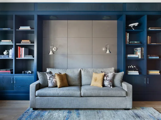 A grey couch sitting in a room with a blue shelving cabinet