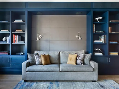 A grey couch sitting in a room with a blue shelving cabinet