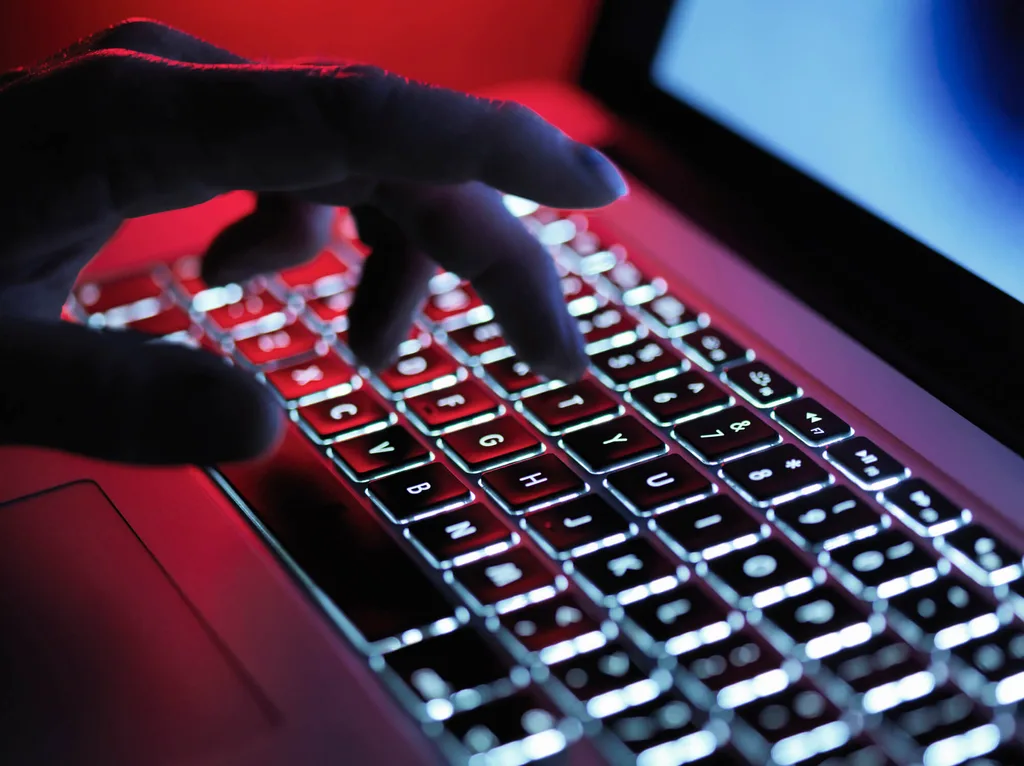 A person typing on a backlit Macbook keyword