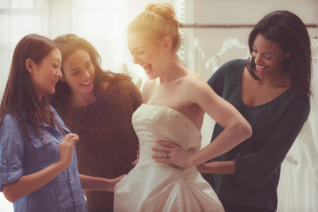 A bridesmaid laughing with bridesmaids with sun shining through the window