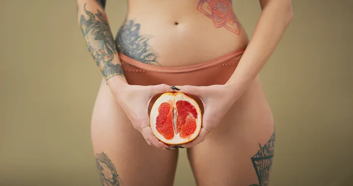 Woman holding a citrus in front of her crotch