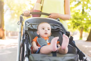 A baby in a pram walking through a park