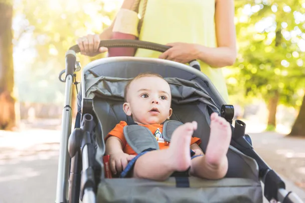 A baby in a pram walking through a park