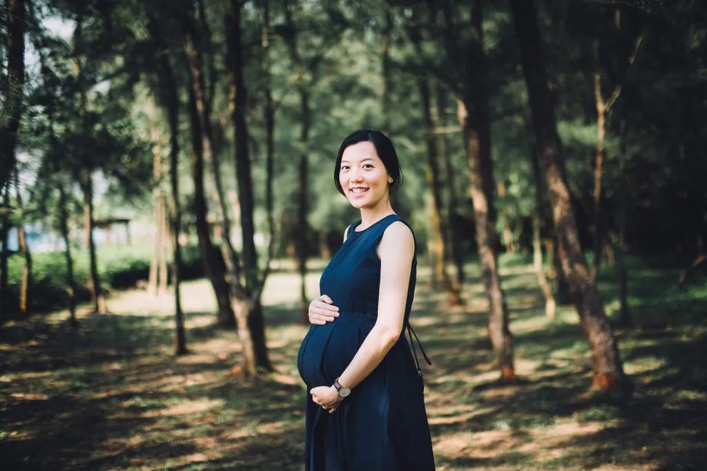Woman in a park holding her pregnant baby bump