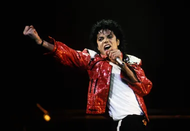 Michael Jackson performing on stage in a red jacket