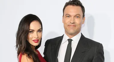 Two people, a woman in a red dress and a man in a suit and tie, smiling at a formal event.