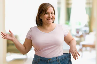 Woman holding waistbands of jeans that are too big