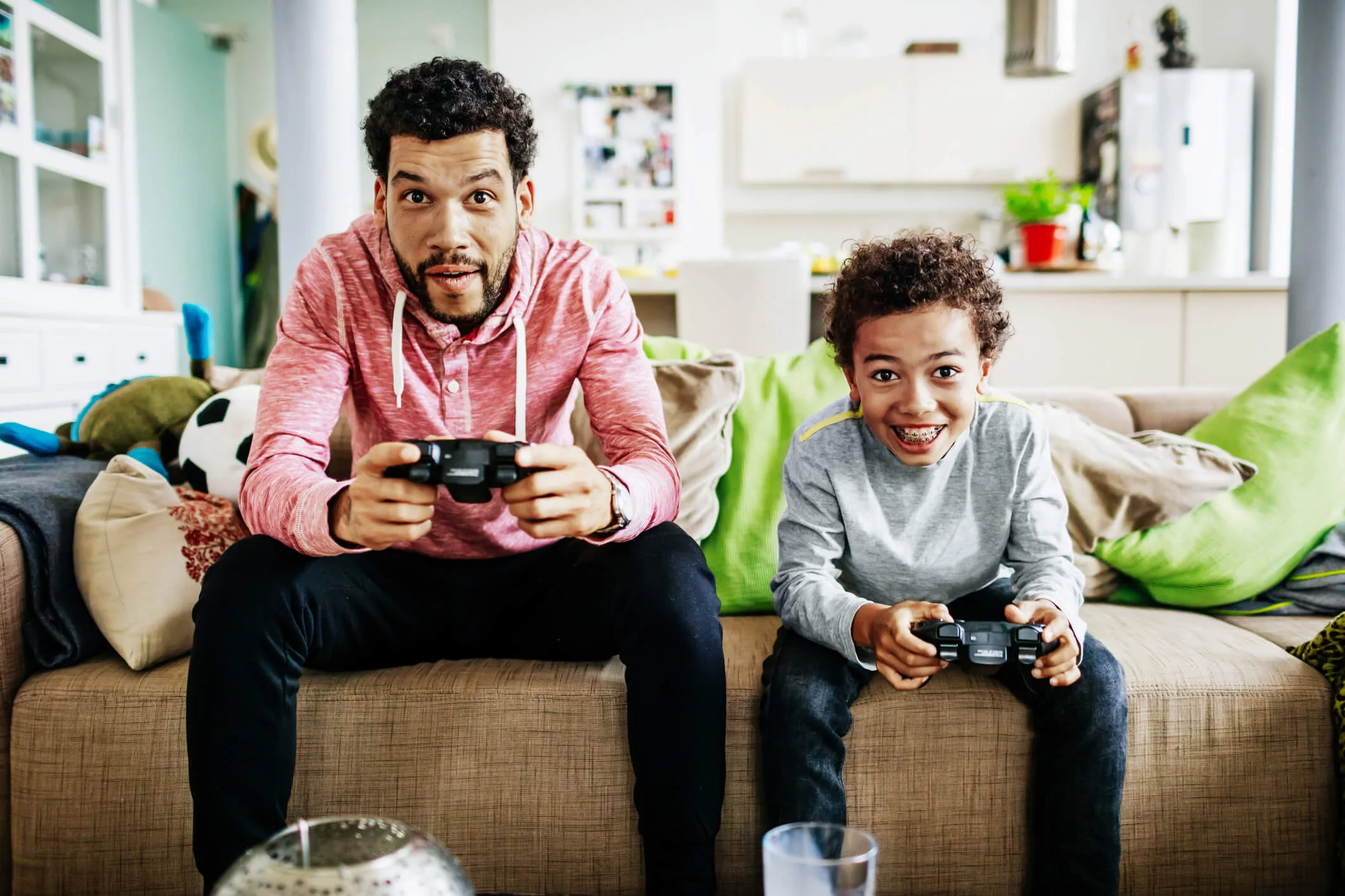 A father and son sitting on the couch playing video games