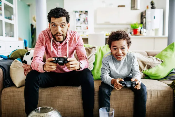 A father and son sitting on the couch playing video games