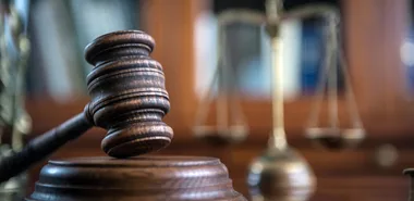 A judge hammer in front of a scale of justice