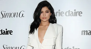 Person in a white outfit posing in front of a Marie Claire backdrop.