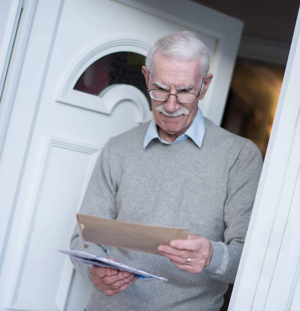 A senior checking his mail at his front door