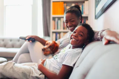 A kid and his mum watching tv together