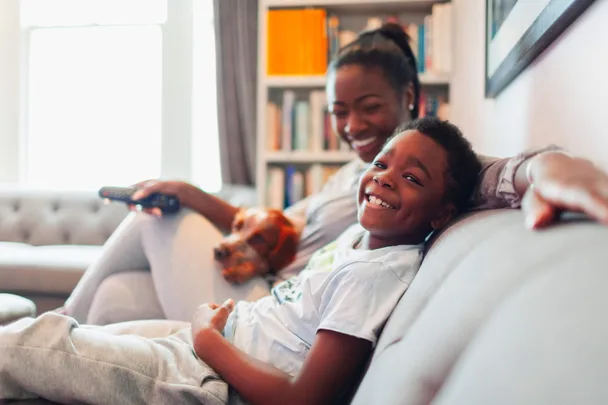 A kid and his mum watching tv together