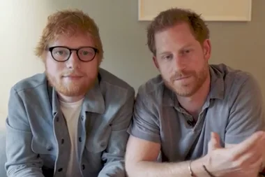 Two men with red hair and beards, one wearing glasses, sitting closely together in a casual setting.