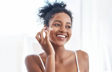 A woman applying face cream on her cheek