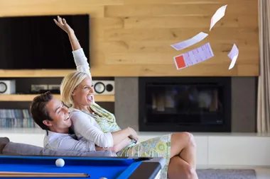 A woman and man throwing a winning lotto ticket in the air