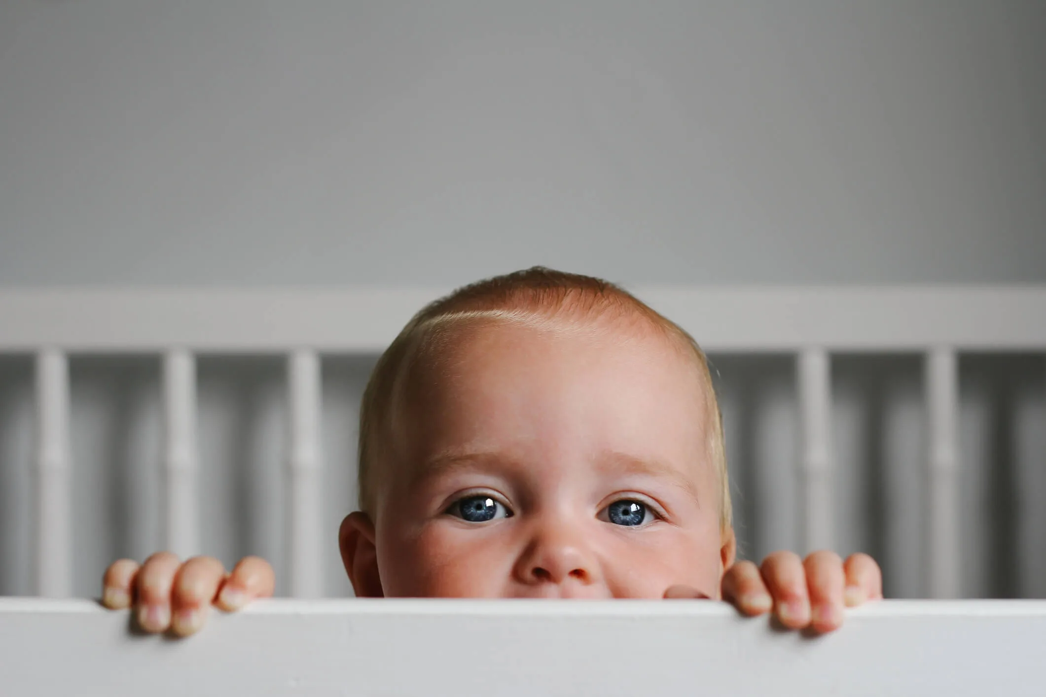 A baby looking over a bed frame