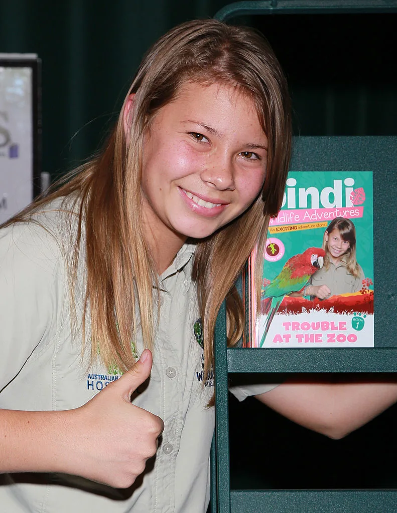 Bindi Irwin giving a thumbs up in front of her book 'Trouble At The Zoo'