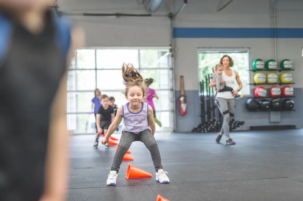 A young girl jumping over road cones