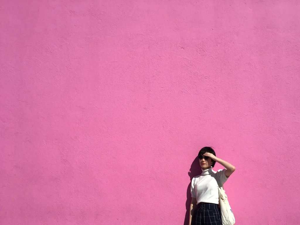 A girl standing in front of a pink background