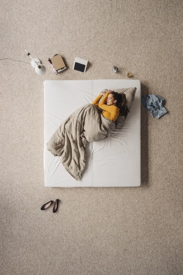 Woman lying on a mattress on a carpeted floor