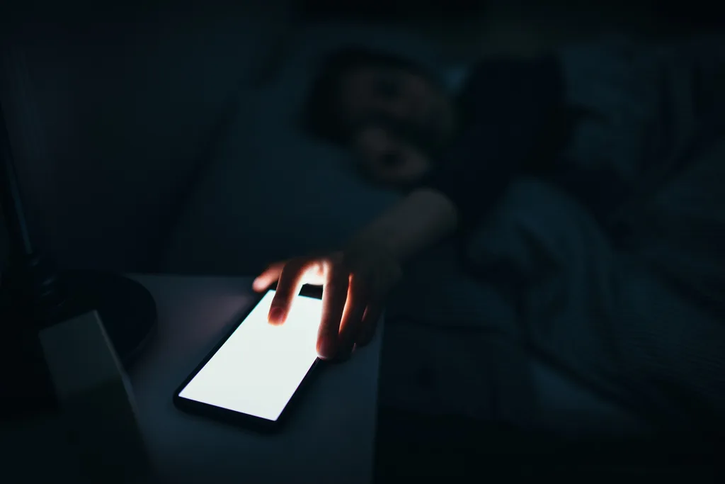 A woman reaching for her phone at night