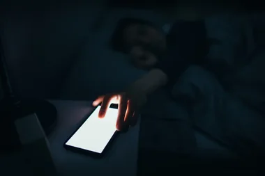 A woman reaching for her phone at night