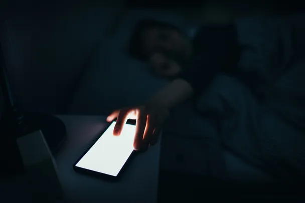 A woman reaching for her phone at night
