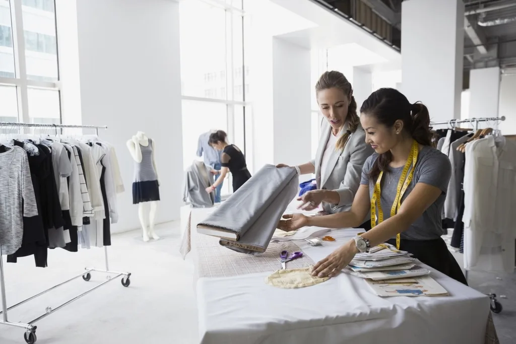 A fashion designer cutting and sewing fabric in a studio