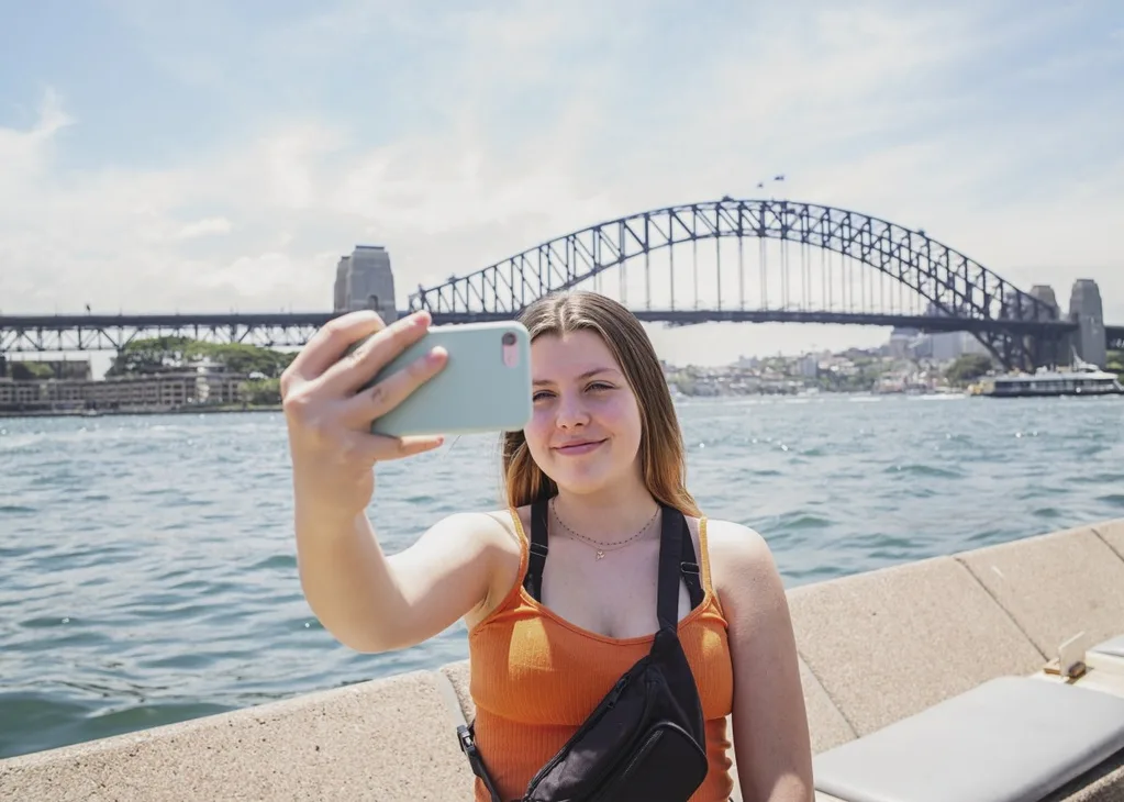 A girl taking selfies in front of a bridge