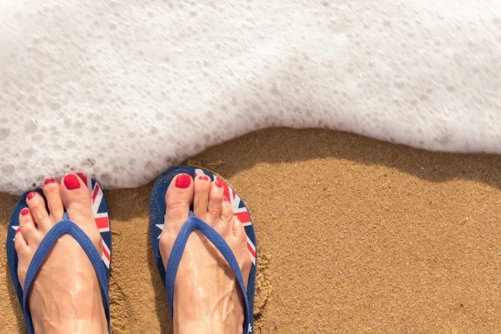 A woman's feet wearing Australian thongs at the beach