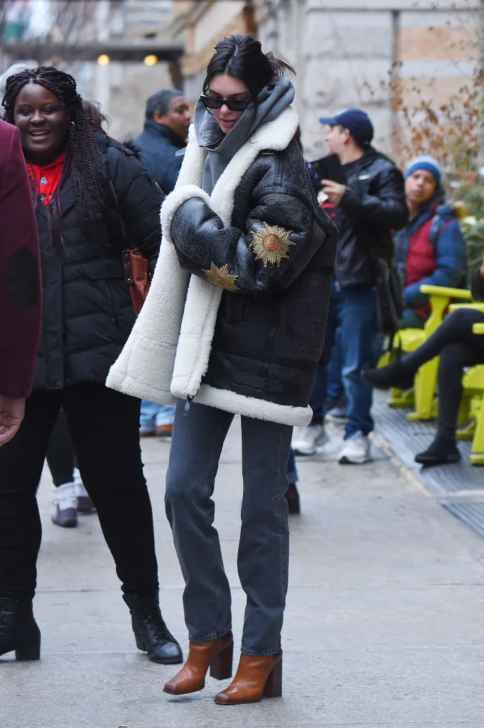 Kendall Jenner wearing a winter coat with denim jeans and boots
