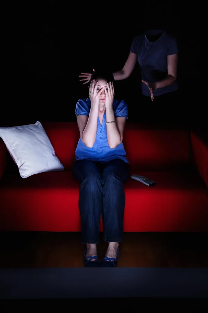 A man sneaking up on a scared woman in the dark