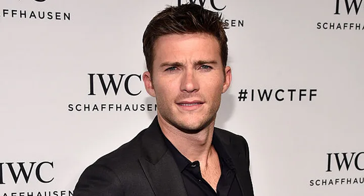 A person in a black suit at an IWC Schaffhausen event, standing in front of a branded backdrop.