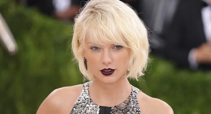 A woman with short blonde hair and dark lipstick wearing a sequined dress at a formal event.