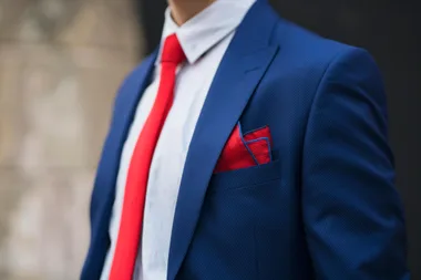 A man with a blue suit, red tie and red pocket squares